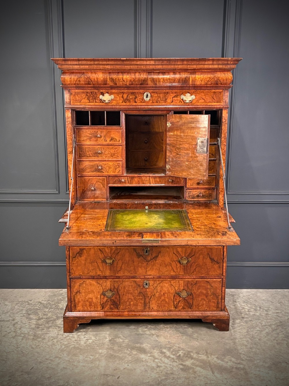 An antique Queen Anne walnut escritoire featuring a drop-front writing surface revealing a fitted interior above a base with drawers. View V