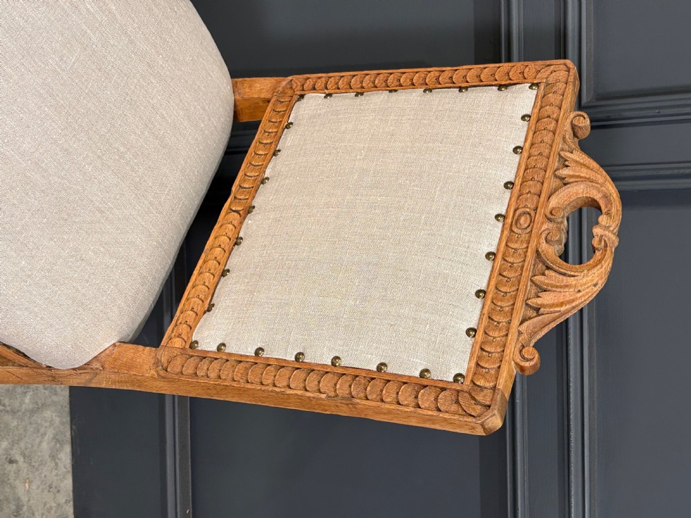 A set of six carved bleached oak dining chairs upholstered in neutral linen fabric with brass stud trimming and turned front legs on ceramic castors. View IX
