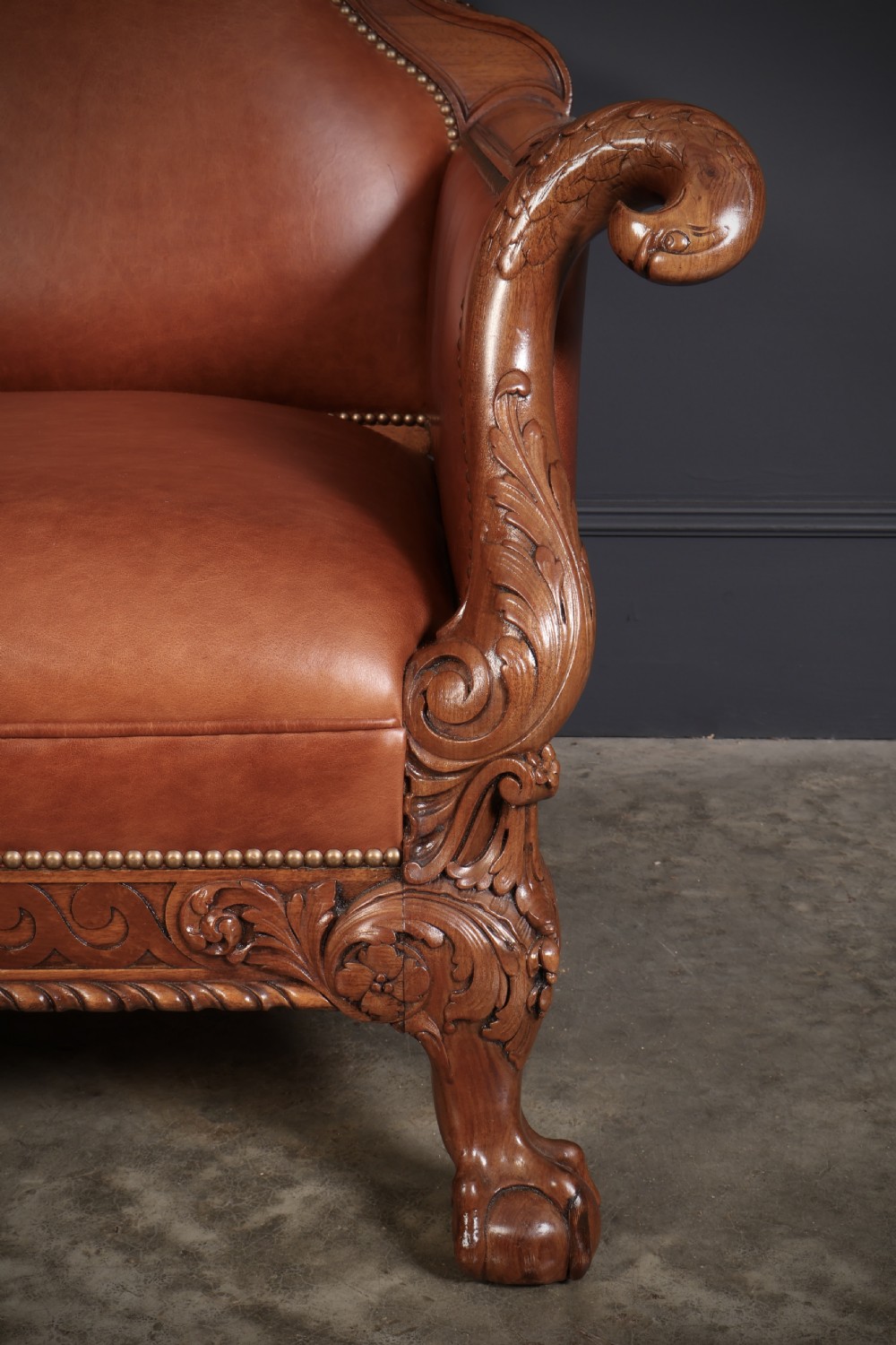 A three-piece lounge suite comprising a three-seater sofa and two matching armchairs upholstered in chestnut brown leather with carved mahogany frames and claw and ball feet. View VII