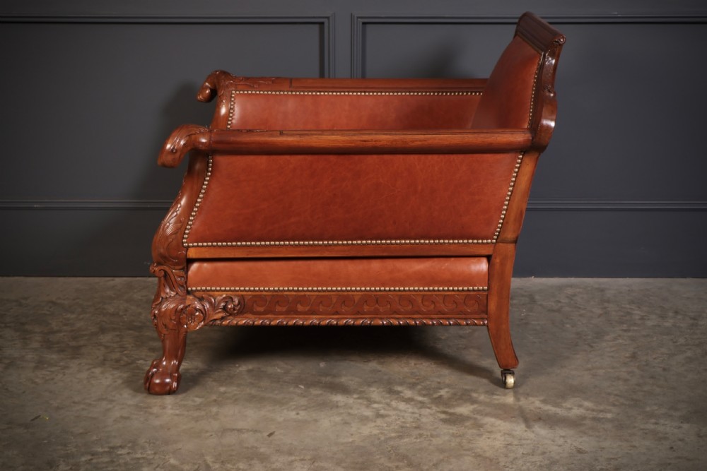 A three-piece lounge suite comprising a three-seater sofa and two matching armchairs upholstered in chestnut brown leather with carved mahogany frames and claw and ball feet. View IX
