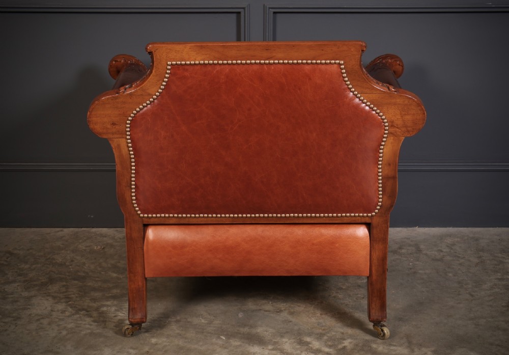 A three-piece lounge suite comprising a three-seater sofa and two matching armchairs upholstered in chestnut brown leather with carved mahogany frames and claw and ball feet. View X