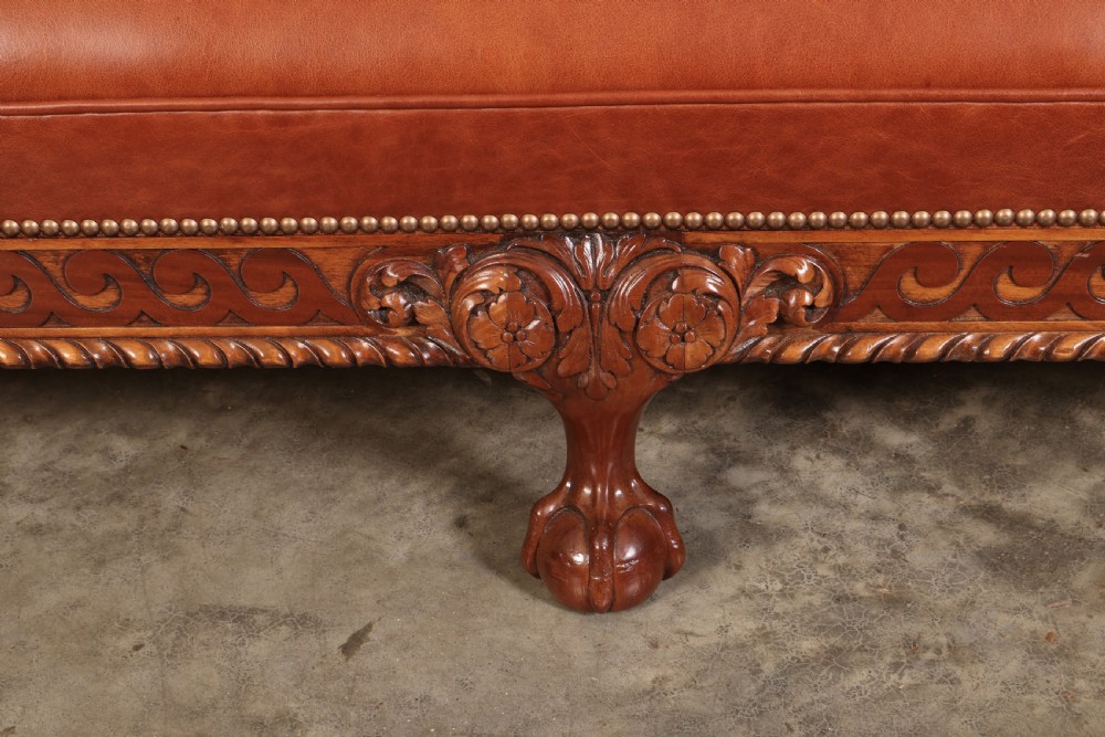 A three-piece lounge suite comprising a three-seater sofa and two matching armchairs upholstered in chestnut brown leather with carved mahogany frames and claw and ball feet. View XV