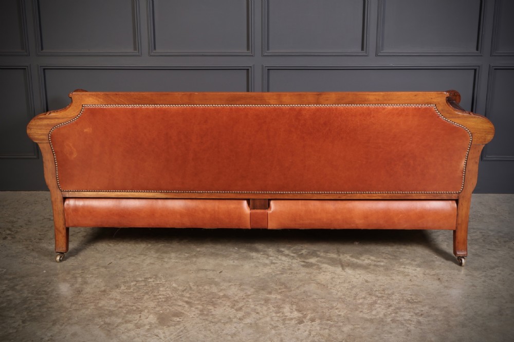 A three-piece lounge suite comprising a three-seater sofa and two matching armchairs upholstered in chestnut brown leather with carved mahogany frames and claw and ball feet. View XVII