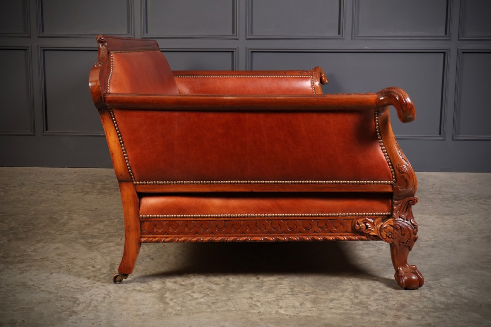 A three-piece lounge suite comprising a three-seater sofa and two matching armchairs upholstered in chestnut brown leather with carved mahogany frames and claw and ball feet. View XVIII