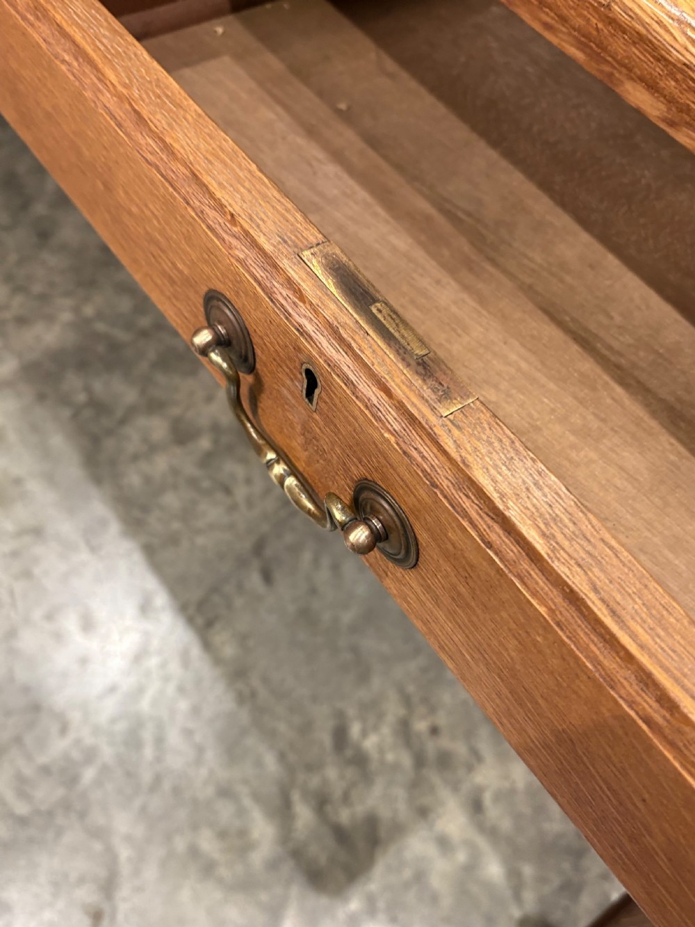 A large oak writing table featuring a green leather top, three frieze drawers with brass drop handles, and four fluted legs. View IX
