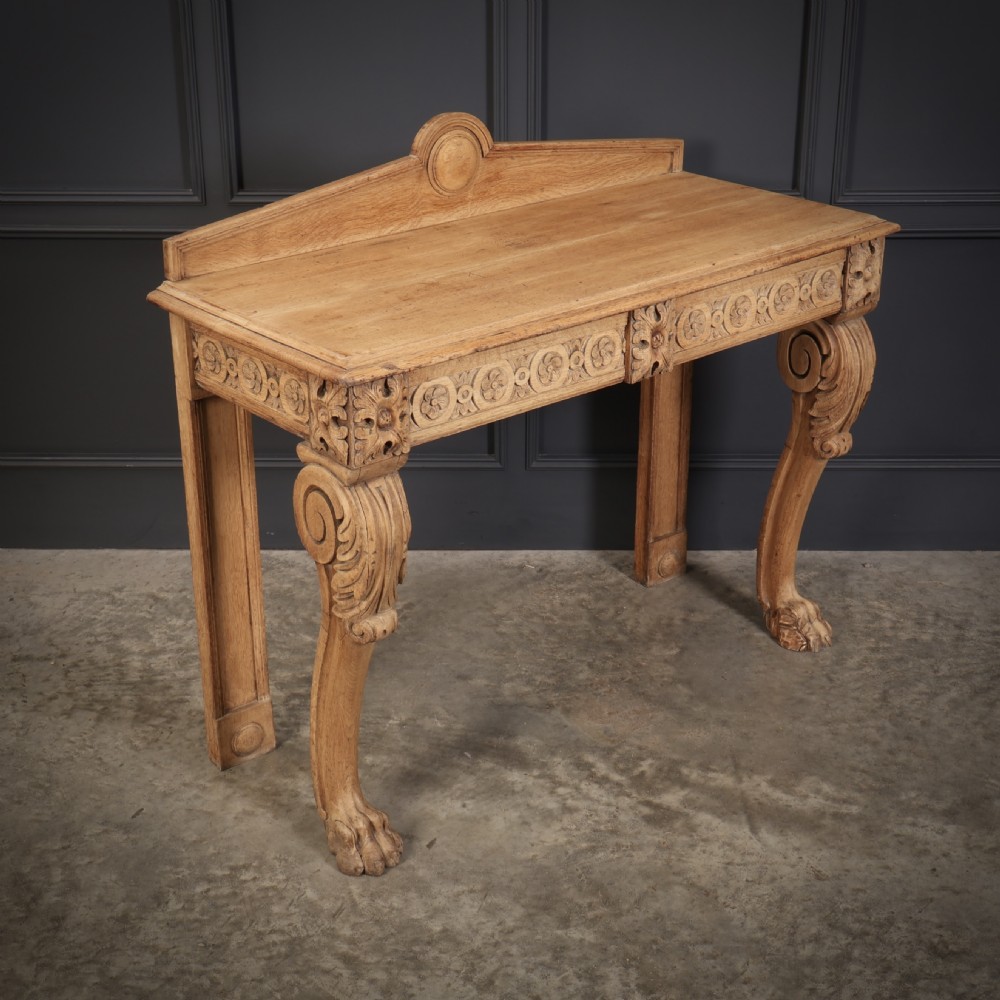 A carved bleached oak console table featuring a raised back gallery, rosette carved frieze, and sculptural monopodium legs terminating in lion paw feet. View VII