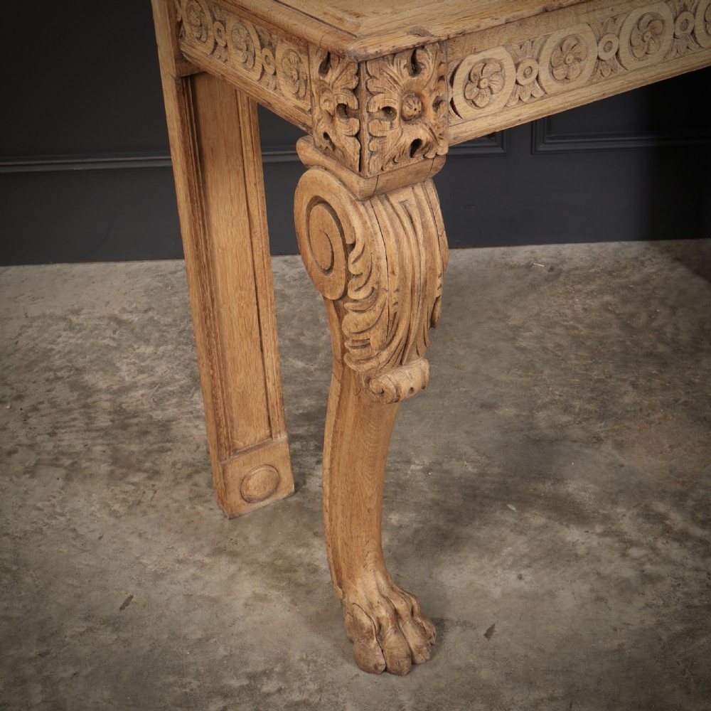 A carved bleached oak console table featuring a raised back gallery, rosette carved frieze, and sculptural monopodium legs terminating in lion paw feet. View IV