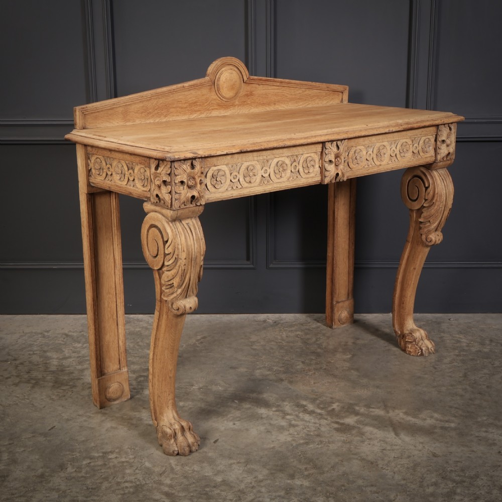A carved bleached oak console table featuring a raised back gallery, rosette carved frieze, and sculptural monopodium legs terminating in lion paw feet. View V