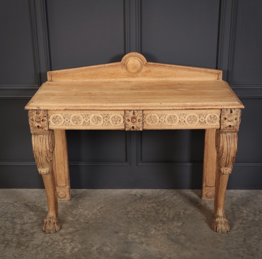 A carved bleached oak console table featuring a raised back gallery, rosette carved frieze, and sculptural monopodium legs terminating in lion paw feet. View VI