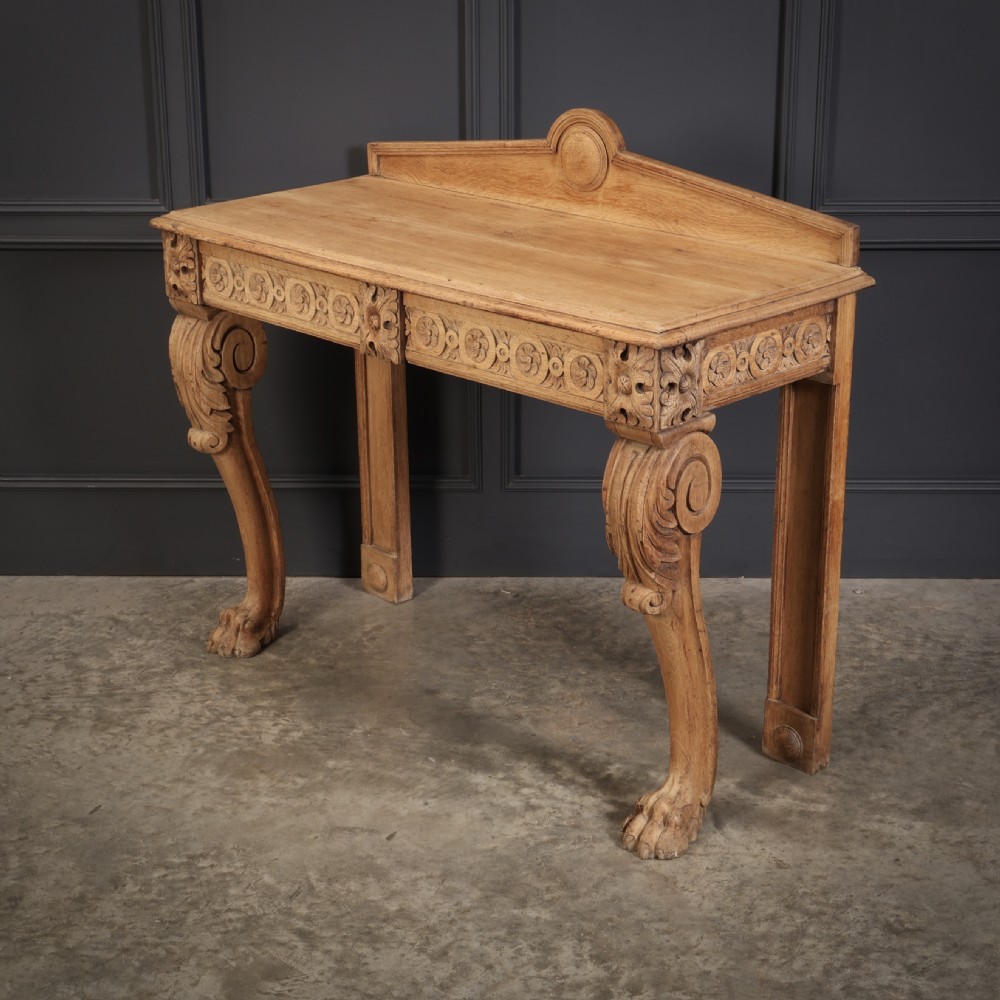 A carved bleached oak console table featuring a raised back gallery, rosette carved frieze, and sculptural monopodium legs terminating in lion paw feet. View IX