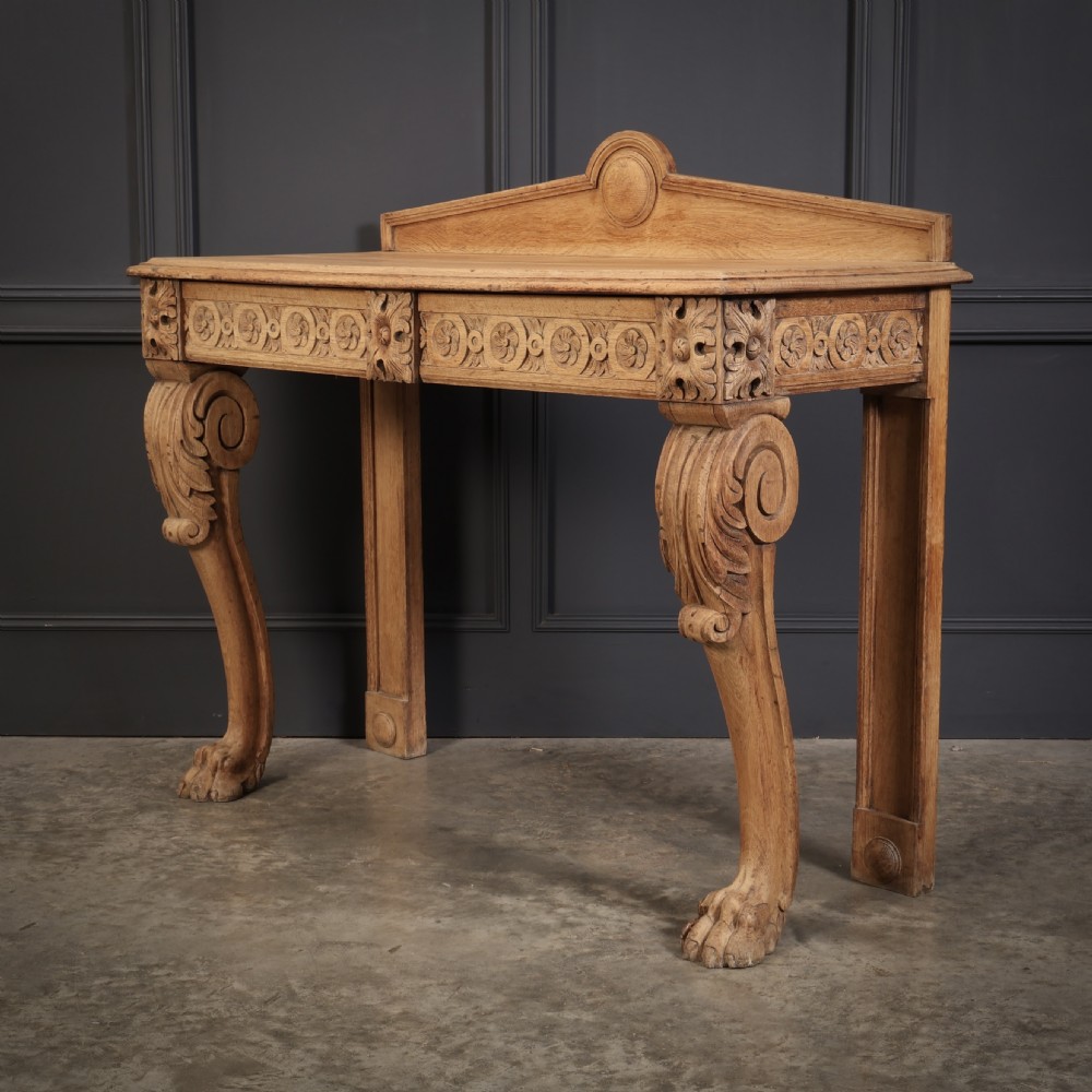 A carved bleached oak console table featuring a raised back gallery, rosette carved frieze, and sculptural monopodium legs terminating in lion paw feet. View X