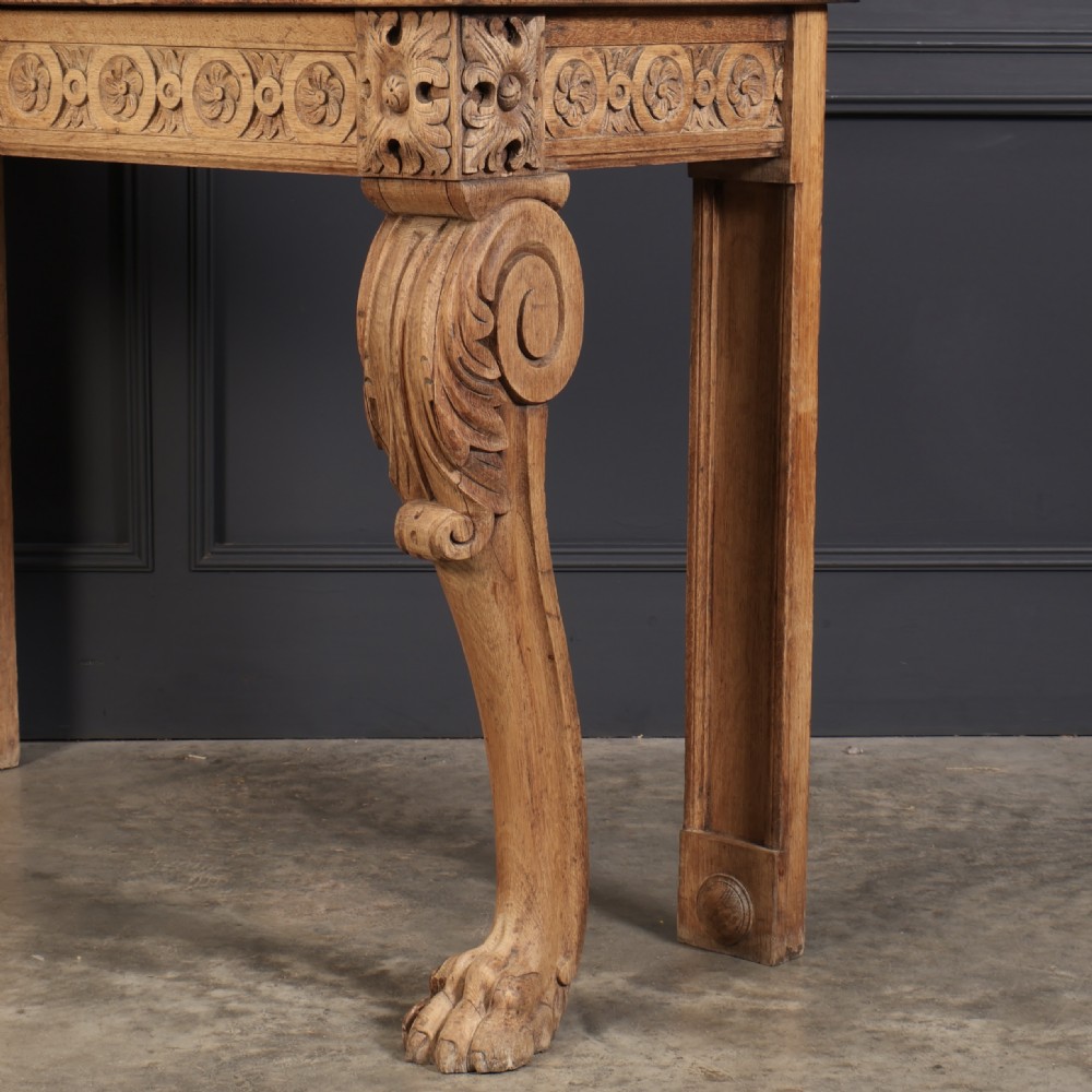 A carved bleached oak console table featuring a raised back gallery, rosette carved frieze, and sculptural monopodium legs terminating in lion paw feet. View XI