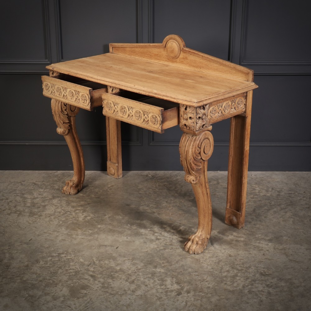 A carved bleached oak console table featuring a raised back gallery, rosette carved frieze, and sculptural monopodium legs terminating in lion paw feet. View XII