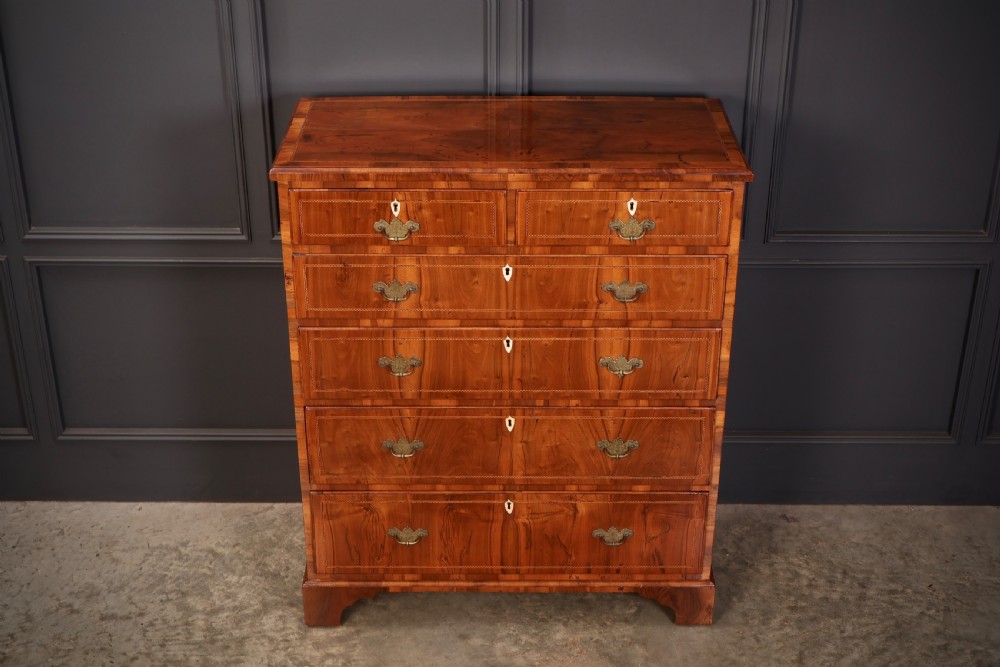 A Georgian walnut chest of drawers with figured grain, brass drop handles, bone escutcheons, and bracket feet. View IV