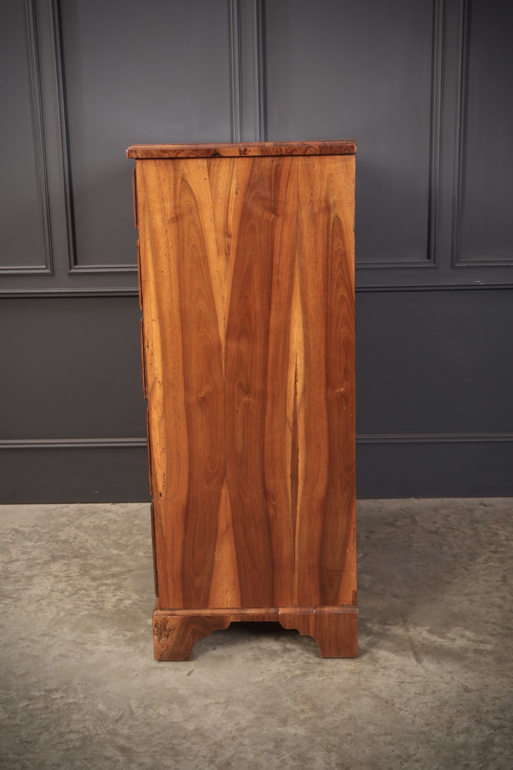A Georgian walnut chest of drawers with figured grain, brass drop handles, bone escutcheons, and bracket feet. View VII