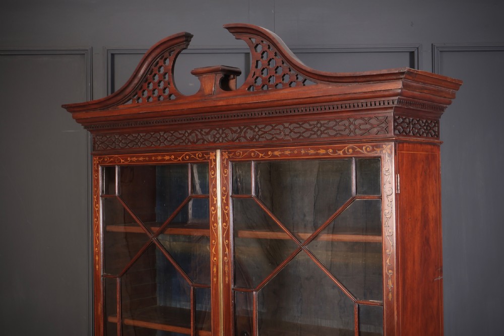 A tall Georgian mahogany bookcase featuring a pierced fretwork pediment, two upper glazed doors with intricate geometric glazing bars, and a lower serpentine chest of three drawers adorned with detailed floral marquetry inlays and brass handles. View XI