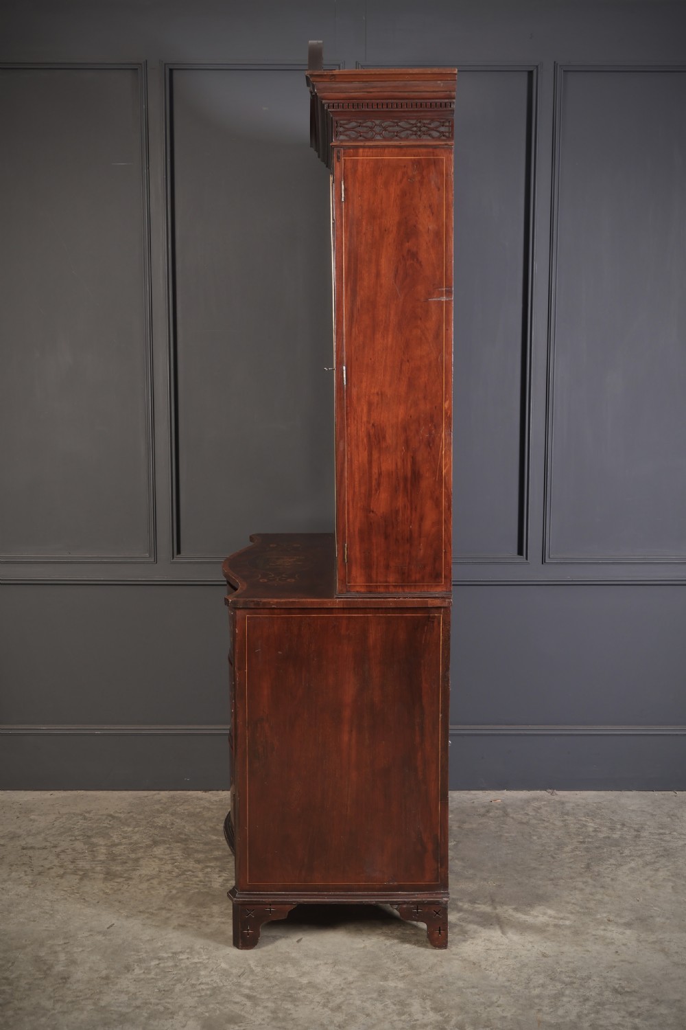 A tall Georgian mahogany bookcase featuring a pierced fretwork pediment, two upper glazed doors with intricate geometric glazing bars, and a lower serpentine chest of three drawers adorned with detailed floral marquetry inlays and brass handles. View XIV