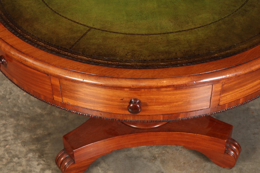 A Victorian circular mahogany drum table featuring a green leather inset top, perimeter frieze drawers with wooden knobs, and a central pedestal base with castors. View II