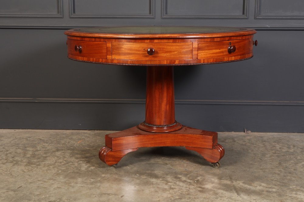 A Victorian circular mahogany drum table featuring a green leather inset top, perimeter frieze drawers with wooden knobs, and a central pedestal base with castors. View III
