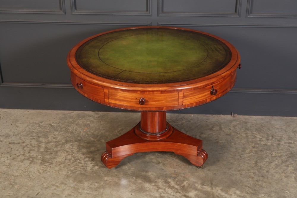 A Victorian circular mahogany drum table featuring a green leather inset top, perimeter frieze drawers with wooden knobs, and a central pedestal base with castors. View IV