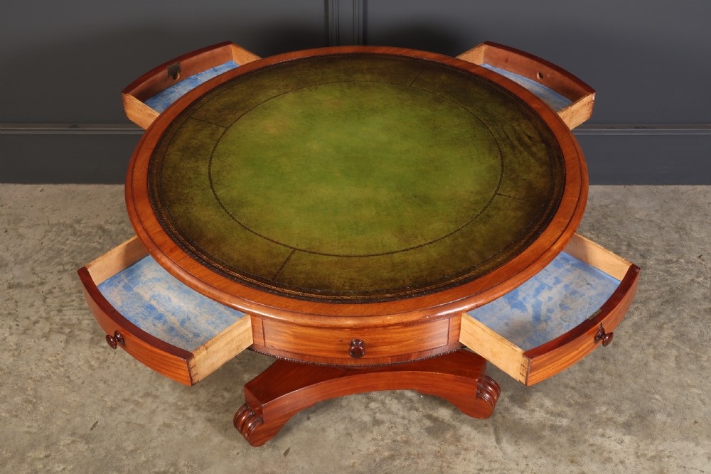 A Victorian circular mahogany drum table featuring a green leather inset top, perimeter frieze drawers with wooden knobs, and a central pedestal base with castors. View V