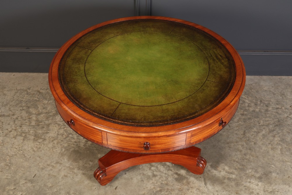 A Victorian circular mahogany drum table featuring a green leather inset top, perimeter frieze drawers with wooden knobs, and a central pedestal base with castors. View VI