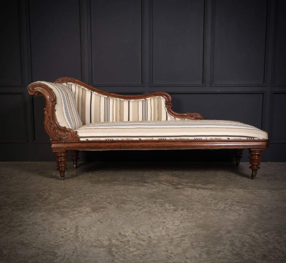 A William IV rosewood chaise longue featuring an asymmetrical scrolled backrest, striped cream and brown fabric upholstery, carved floral accents, turned legs, and brass castors. View IV