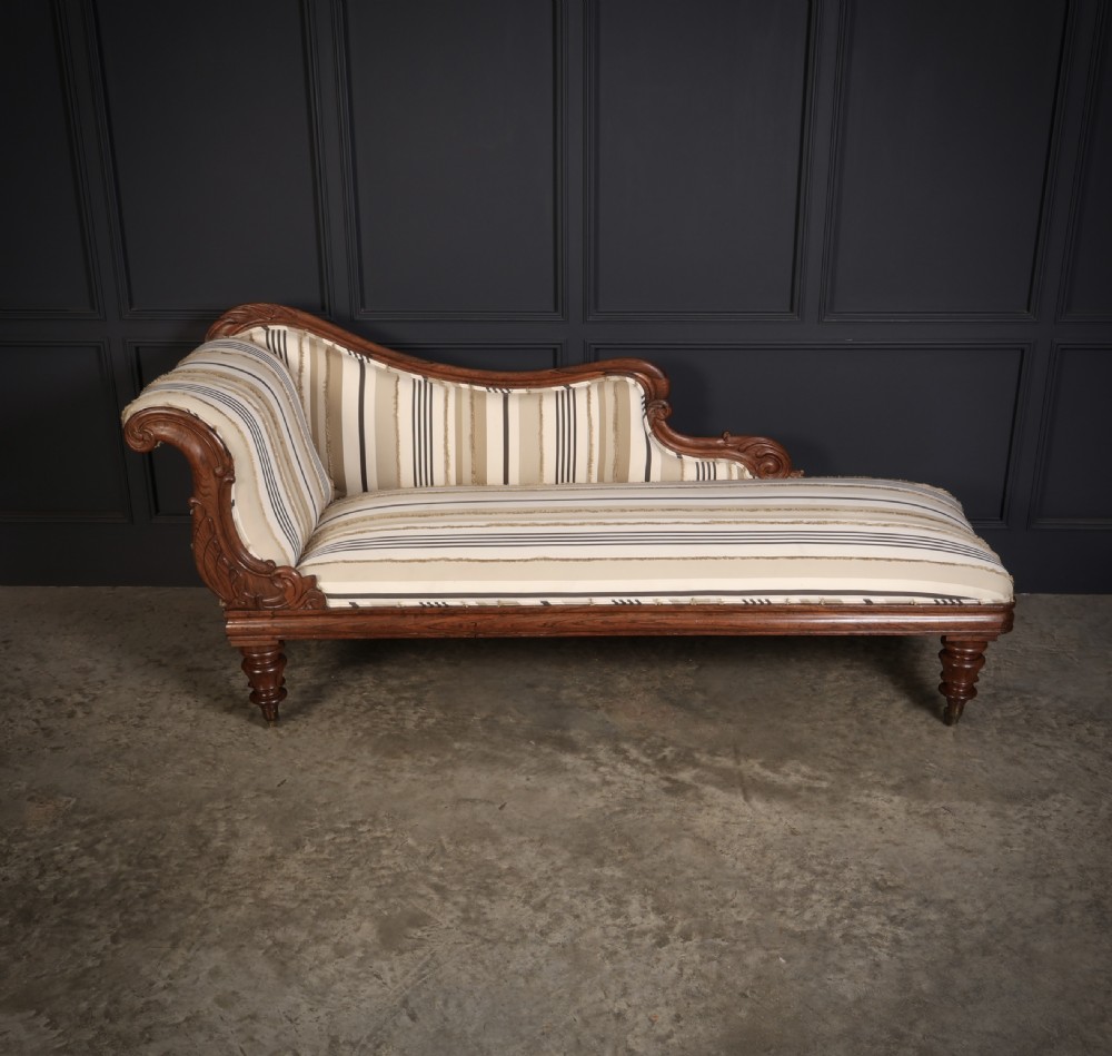 A William IV rosewood chaise longue featuring an asymmetrical scrolled backrest, striped cream and brown fabric upholstery, carved floral accents, turned legs, and brass castors. View VI