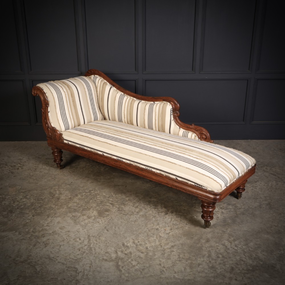 A William IV rosewood chaise longue featuring an asymmetrical scrolled backrest, striped cream and brown fabric upholstery, carved floral accents, turned legs, and brass castors. View VII