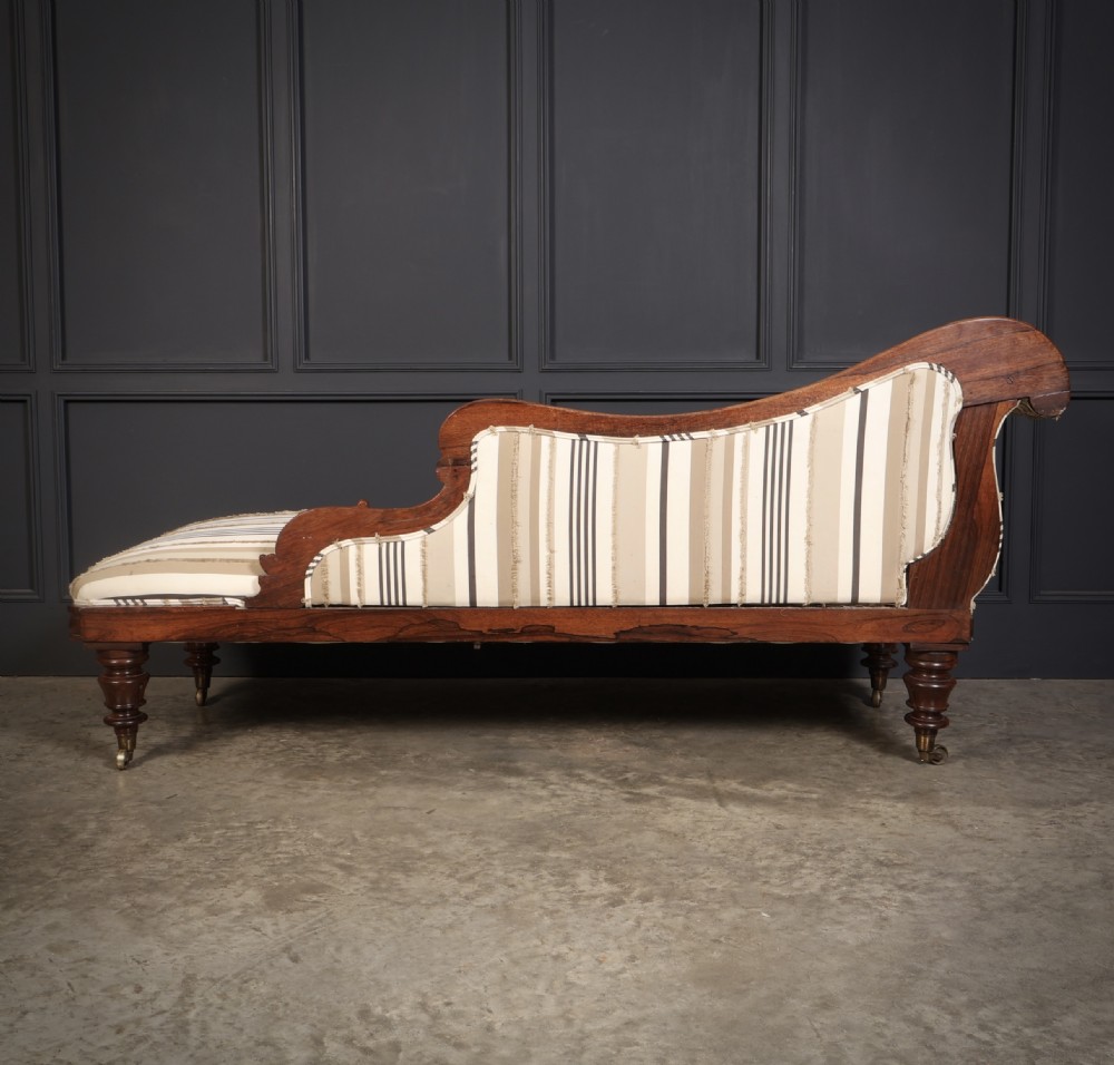 A William IV rosewood chaise longue featuring an asymmetrical scrolled backrest, striped cream and brown fabric upholstery, carved floral accents, turned legs, and brass castors. View XII