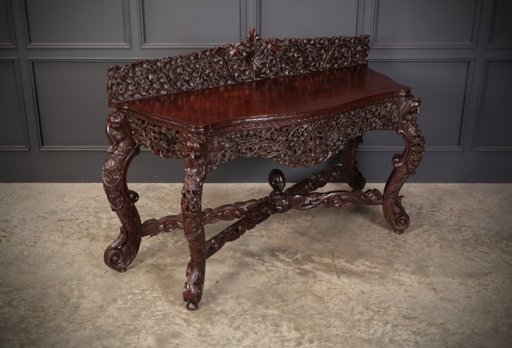 A carved dark padauk wood console table featuring openwork floral fretwork, a raised gallery back, and carved cabriole legs. View II