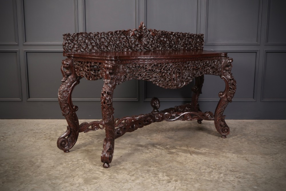 A carved dark padauk wood console table featuring openwork floral fretwork, a raised gallery back, and carved cabriole legs.