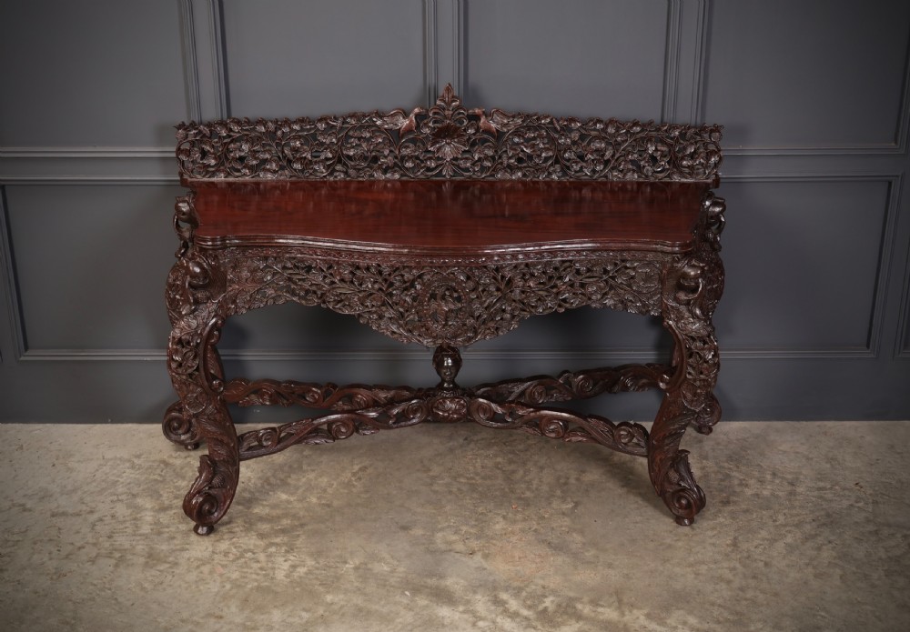 A carved dark padauk wood console table featuring openwork floral fretwork, a raised gallery back, and carved cabriole legs. View III