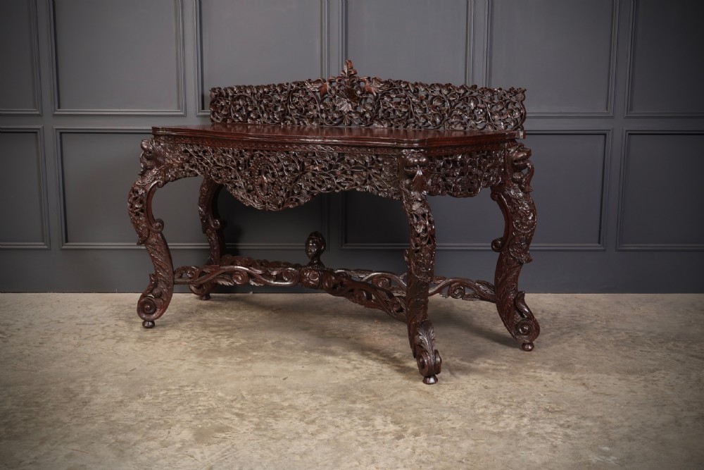 A carved dark padauk wood console table featuring openwork floral fretwork, a raised gallery back, and carved cabriole legs. View VIII