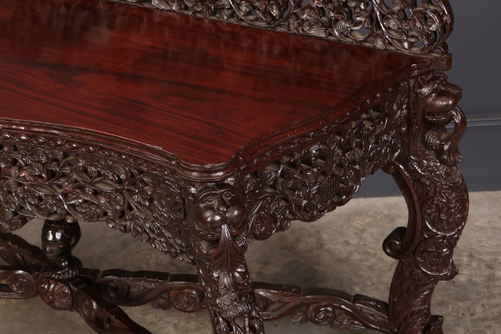 A carved dark padauk wood console table featuring openwork floral fretwork, a raised gallery back, and carved cabriole legs. View IX