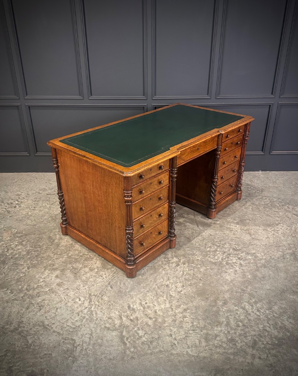 A Victorian figured walnut pedestal desk featuring a green leather writing surface, turned drawer knobs, and carved barley twist pilasters. View III
