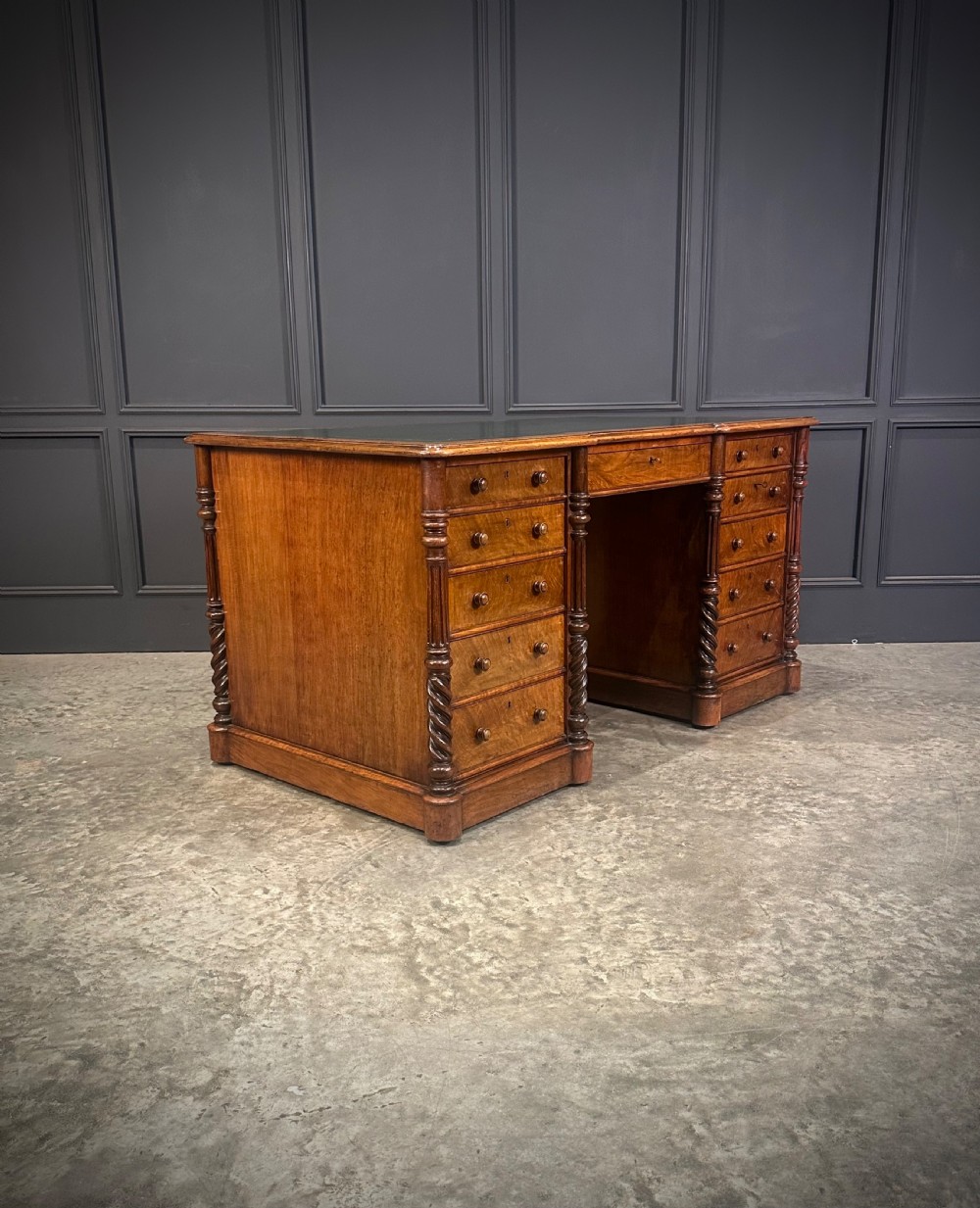 A Victorian figured walnut pedestal desk featuring a green leather writing surface, turned drawer knobs, and carved barley twist pilasters. View II