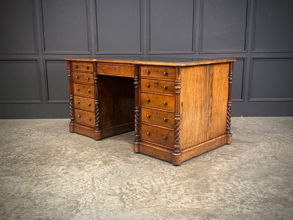 A Victorian figured walnut pedestal desk featuring a green leather writing surface, turned drawer knobs, and carved barley twist pilasters. View VII