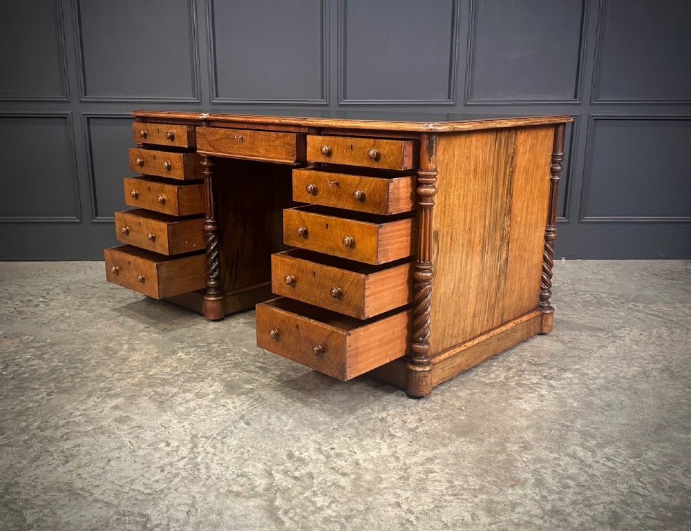 A Victorian figured walnut pedestal desk featuring a green leather writing surface, turned drawer knobs, and carved barley twist pilasters. View IX