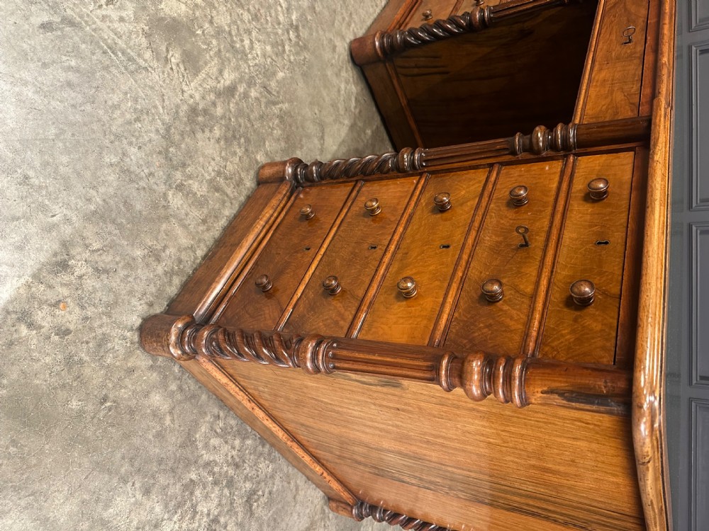A Victorian figured walnut pedestal desk featuring a green leather writing surface, turned drawer knobs, and carved barley twist pilasters. View XI