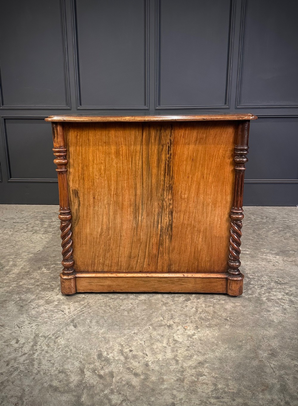 A Victorian figured walnut pedestal desk featuring a green leather writing surface, turned drawer knobs, and carved barley twist pilasters. View XII