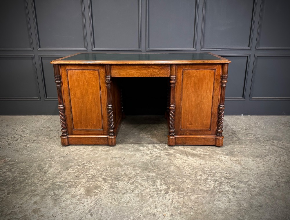 A Victorian figured walnut pedestal desk featuring a green leather writing surface, turned drawer knobs, and carved barley twist pilasters. View XIII