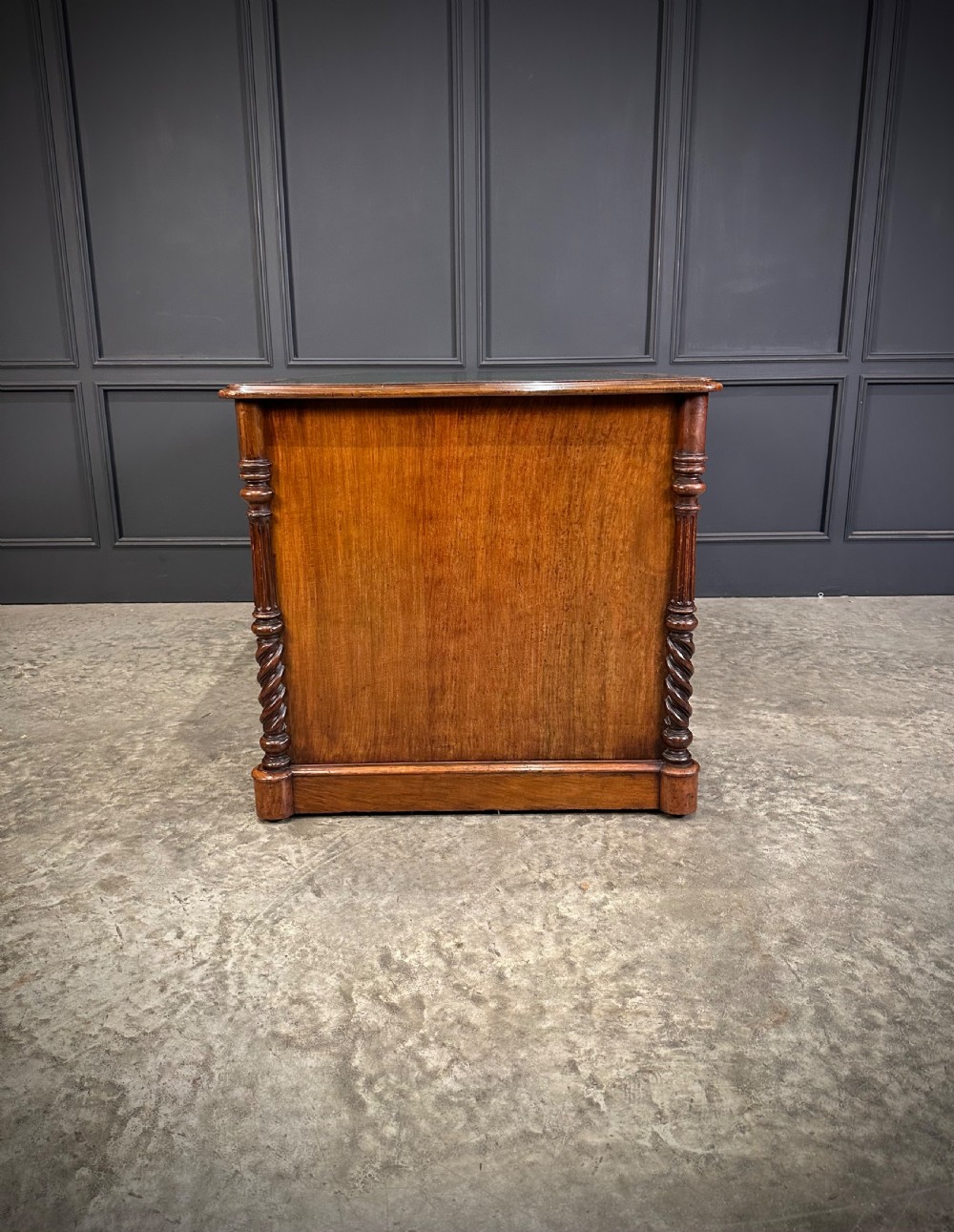 A Victorian figured walnut pedestal desk featuring a green leather writing surface, turned drawer knobs, and carved barley twist pilasters. View XIV