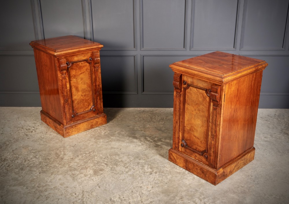 A matching pair of Victorian figured walnut pedestal cabinets featuring carved corbels, panelled doors with decorative line inlay, and sturdy plinth bases. View II