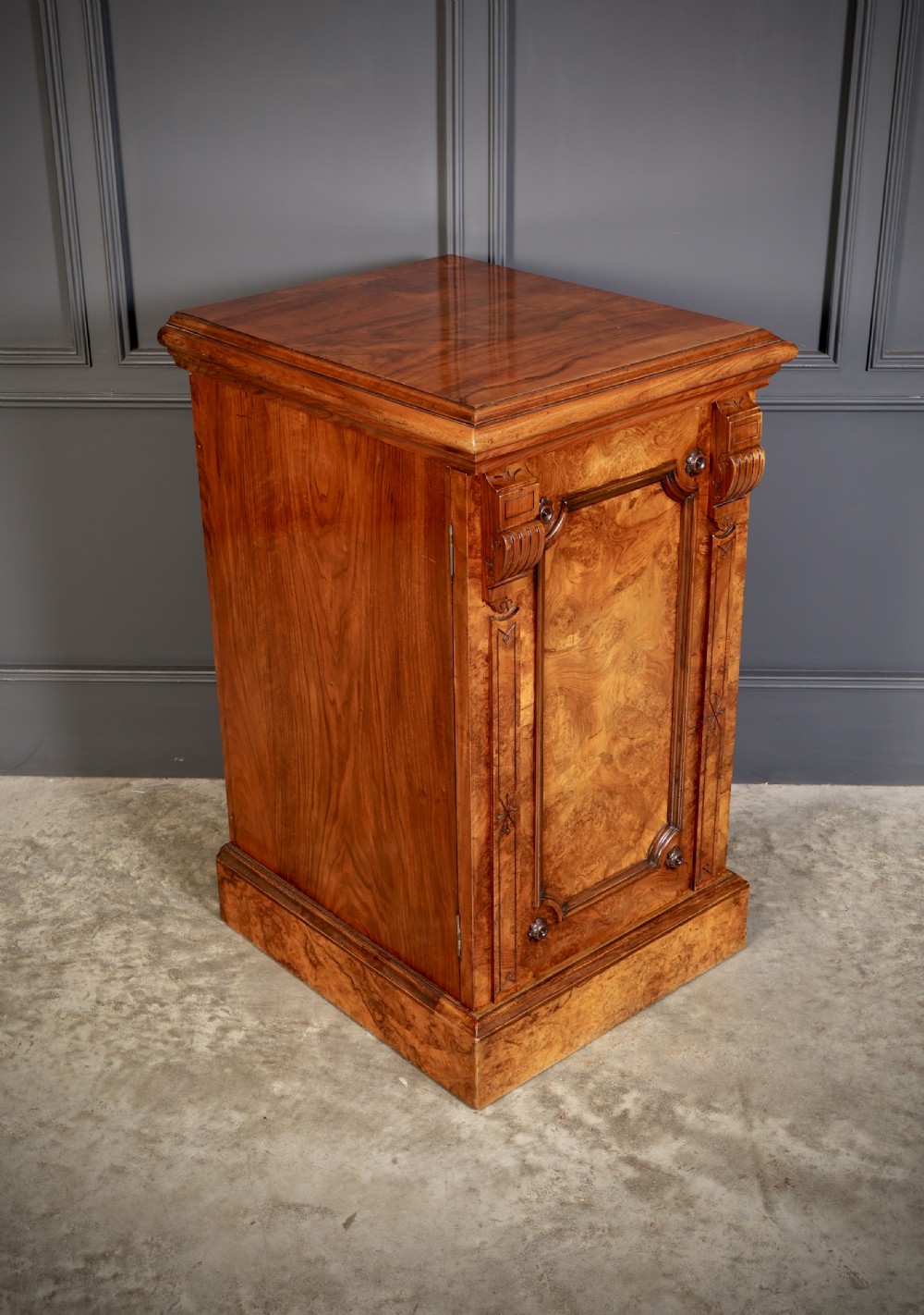 A matching pair of Victorian figured walnut pedestal cabinets featuring carved corbels, panelled doors with decorative line inlay, and sturdy plinth bases. View VII