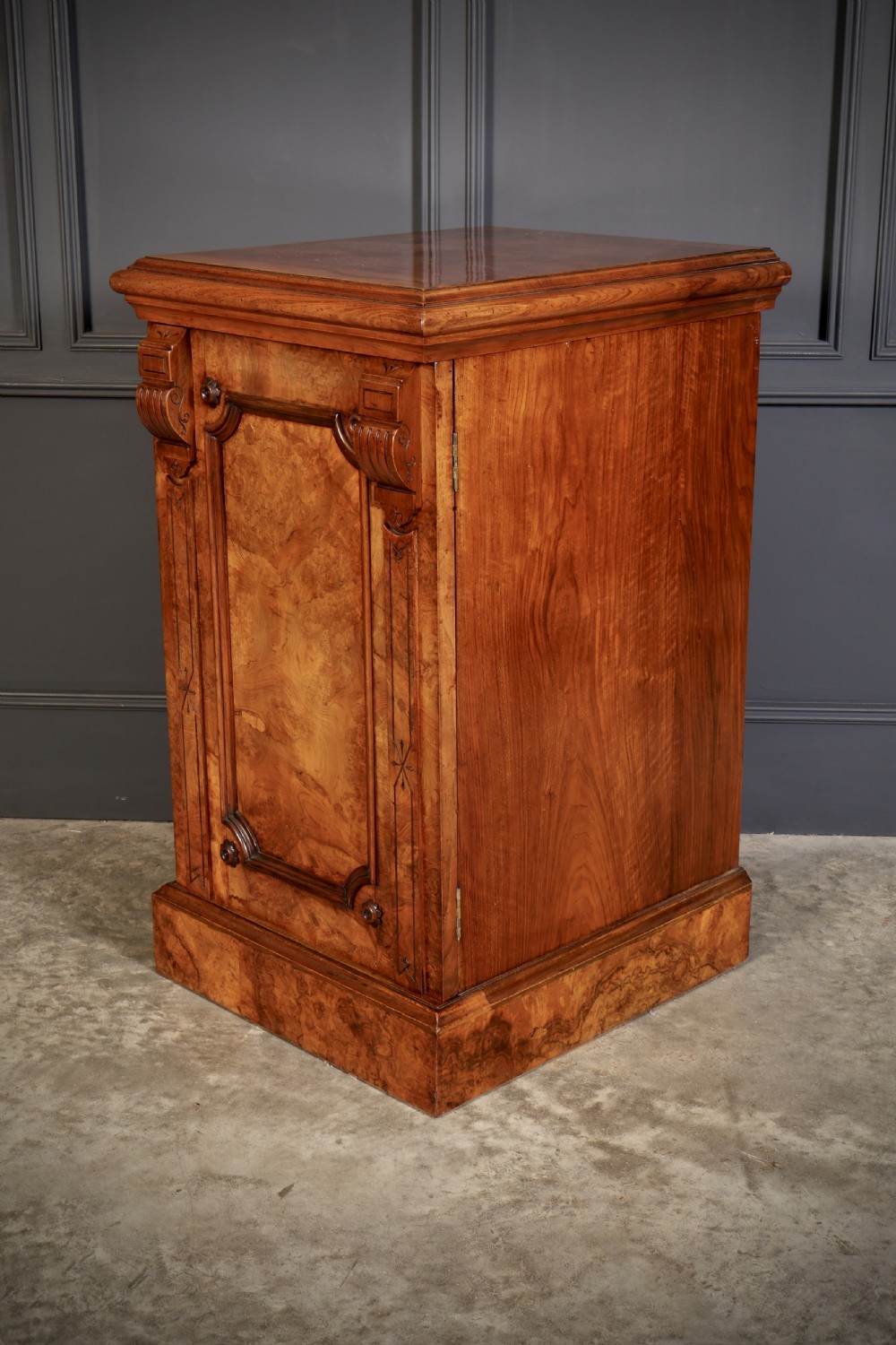 A matching pair of Victorian figured walnut pedestal cabinets featuring carved corbels, panelled doors with decorative line inlay, and sturdy plinth bases. View X
