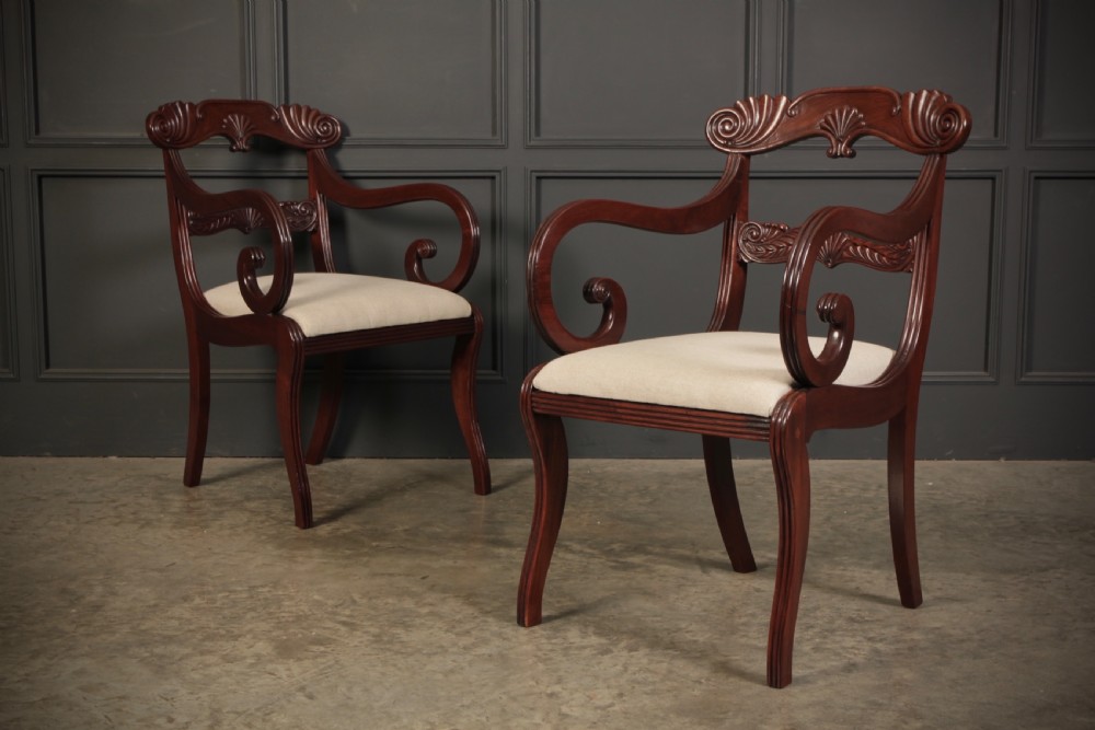 A set of eight carved mahogany Regency dining chairs featuring scroll arms, carved crest rails, and cream upholstered seats. View XVI
