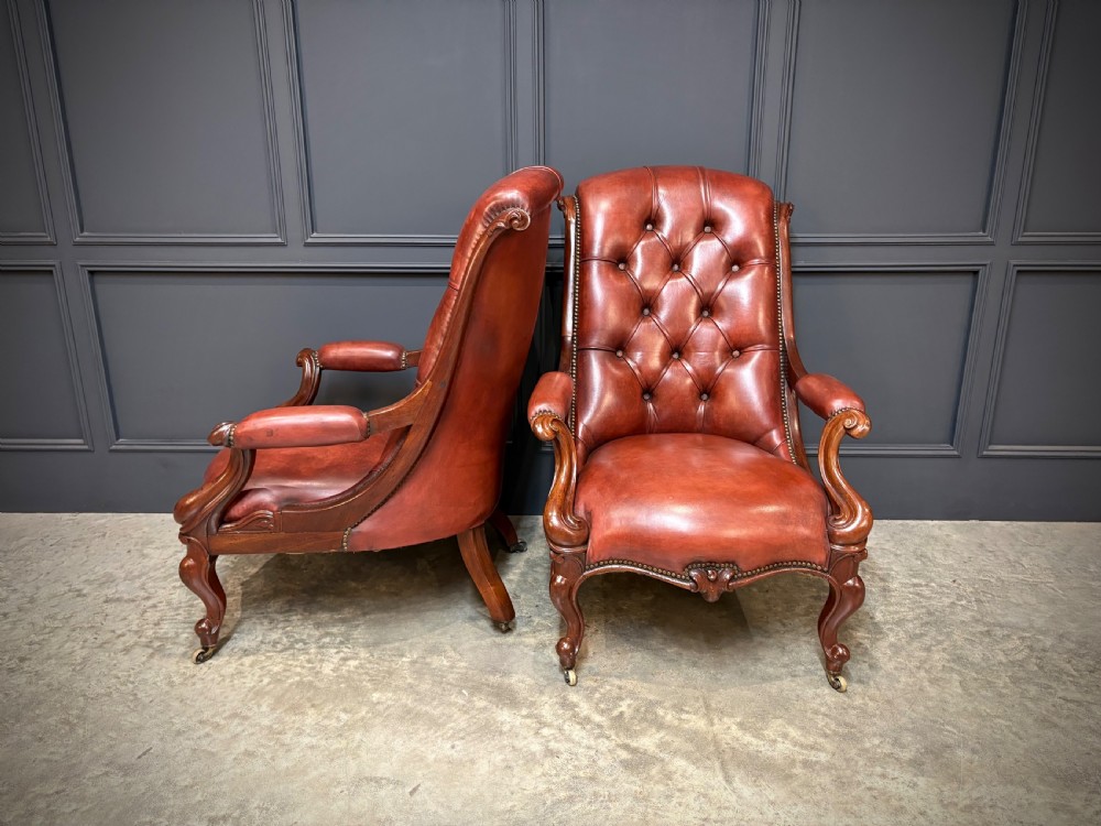 A pair of Victorian library armchairs upholstered in deep-buttoned reddish-brown leather with carved mahogany frames and brass castors. View III