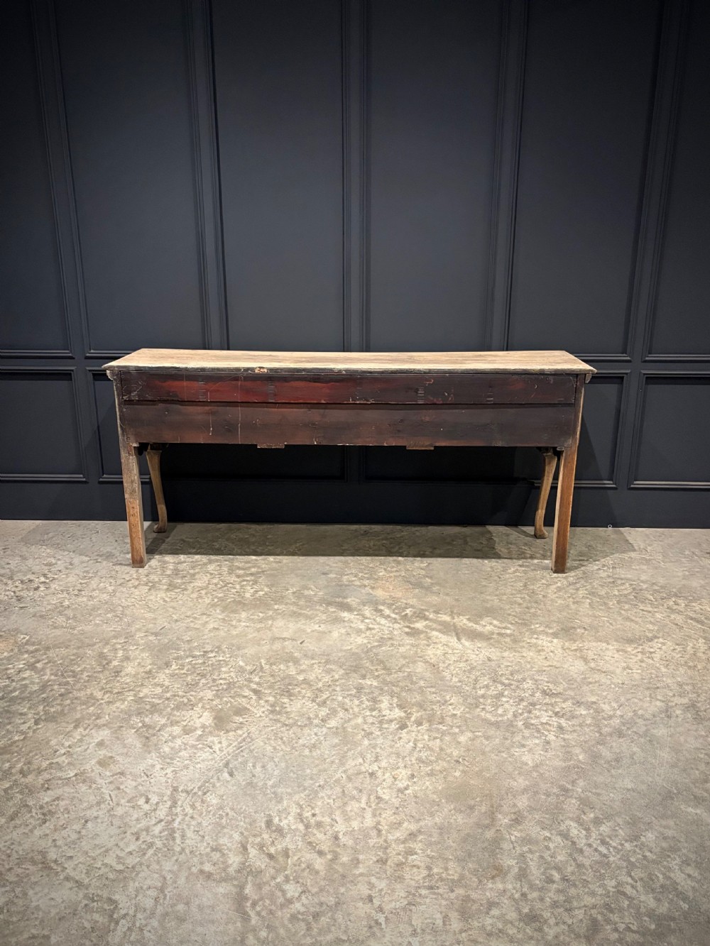 An 18th-century carved oak dresser base featuring three drawers with detailed relief carving, brass handles, shaped apron, cabriole front legs, and a pale bleached finish. View V