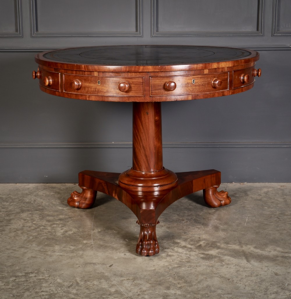 A circular William IV mahogany rotating drum table featuring a black leather inset top, frieze drawers with turned handles, a thick turned column, and a triform base with carved paw feet. View V